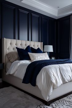 a bedroom with dark blue walls, white bedding and an upholstered headboard