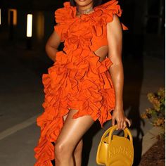 a woman in an orange dress holding a yellow purse