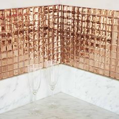 two champagne glasses sitting on top of a counter next to a tiled backsplash