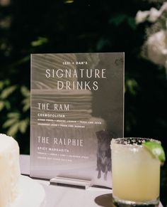 a book sitting on top of a table next to a glass filled with liquid and a drink