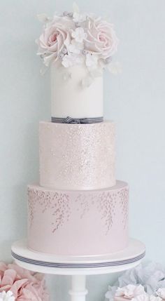 a three tiered wedding cake with pink flowers on the top and silver trimmings