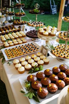 a table topped with lots of cupcakes covered in frosting and toppings