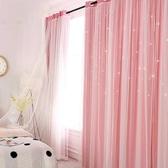 a bedroom decorated in pink and white with polka dots on the bed, curtains, and clock