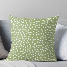 a green and white polka dot pillow on a couch with two throw pillows next to it