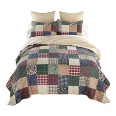 a bed with two pillows on top of it and a quilted comforter in the middle