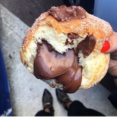 a person holding a half eaten chocolate covered doughnut