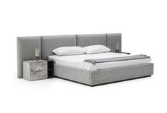 an upholstered bed with two nightstands next to it