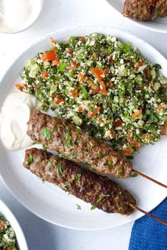 meat skewers with vegetables and yogurt on a white plate