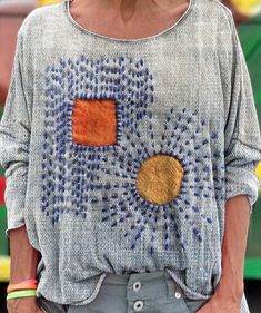 a close up of a person wearing a sweater with an orange and blue design on it