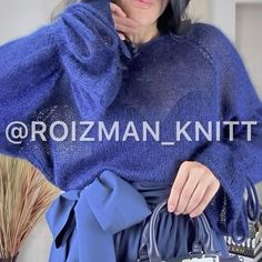 a woman wearing a blue sweater and holding a handbag in front of her face