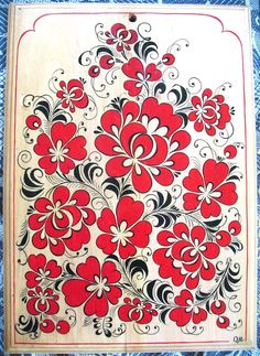 a red and black floral design on a white board with blue fabric in the background