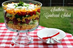 a glass bowl filled with salad sitting on top of a red and white checkered table cloth