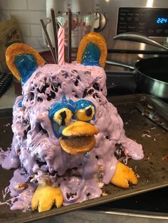 a cake shaped like a monster with frosting on it's face and ears