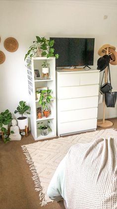 a bedroom with white furniture and lots of plants