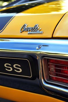 the rear end of a yellow and black car with chrome lettering on it's license plate