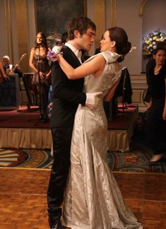 a man and woman are dancing on the dance floor in formal dress clothes with their arms around each other