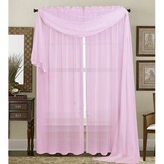 a pink curtain hanging from the side of a window in front of a dresser and mirror