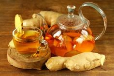 a glass tea pot filled with liquid next to sliced bananas and ginger on a wooden table