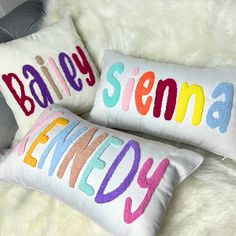 two personalized pillows on a fluffy white furnishing with the word'bailey'in multicolored letters