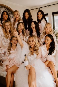 the bridesmaids are all dressed in white dresses and holding their champagne bottles together