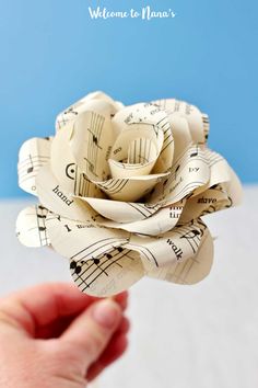 someone is holding up a paper rose made out of sheet music notes