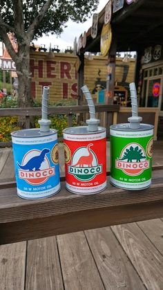 three cans of paint sitting on top of a wooden bench