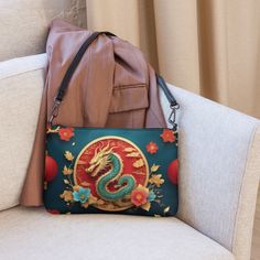 🐉Keep your style on point and your hands free with our Women's Versatile Crossbody Bag/Purse with a Gold, Teal & Red Mystical Dragon Design. It's made of premium faux leather and features dark gray hardware. Thanks to the zip-top closure and multiple inside pockets, you can keep your essentials secure and organized. Transform this crossbody bag with removable wrist and shoulder straps to style it for day-to-night looks. * Outer fabric: faux leather  * Lining: 100% polyester * 11″ × 8″ × 1.5″ (27.9 cm × 20.3 cm × 3.8 cm) * Dark gray hardware * Zip-top closure * Inside zip and slip pockets * Adjustable, removable wrist and shoulder straps * Strap drop length: 14″- 27″ Handheld Mobile Phone Bag As Gift, Crossbody Clutch Gift, Handheld Shoulder Bag With Cell Phone Pocket As Gift, Handheld Shoulder Bag With Cell Phone Pocket, Zipper Pouch Shoulder Bag For Gift, Shoulder Bag With Zipper Pouch For Gifts, Gift Shoulder Bag With Zipper Pouch, Handheld Bags As Gifts, Handheld Bags With Removable Pouch For Personal Use