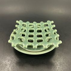 a green plate sitting on top of a black table with holes in the center and sides