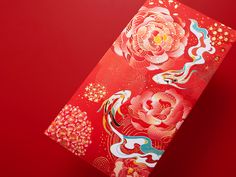 a red and gold chinese paper with flowers on it, sitting against a red background