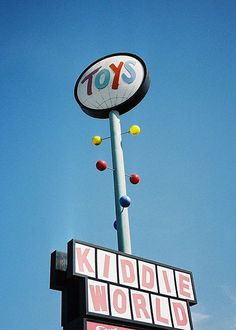 a toy store sign with the word kiddie world on it's side and balls in the air