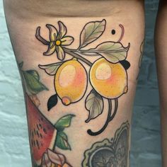 a close up of a person's legs with tattoos on them and fruit in the background