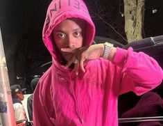 a man in a pink hoodie making a funny face with his hand on his hip