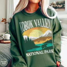 Show off your love of Alaska and one of our nation's most majestic national parks in our Kobuk Valley National Park Sweatshirt! This comfy crewneck is all about embracing the great outdoors, featuring a custom vintage design that showcases the grandeur of the Alaskan Wilderness and the vast mountain terrain of the Kobuk Valley itself! The Gildan 18000 50/50 blend fabric has that comfy, lived-in feel, that's like a hug every time you put it on! Now you can take a bit of Kobuk with you wherever yo Kobuk Valley National Park, Ohio Sweatshirt, National Park Sweatshirt, Maine Trip, Cuyahoga Valley National Park, Maine Vacation, Tree Sweater, Blue Ridge Parkway, Beautiful Park