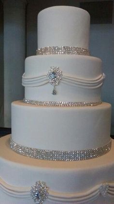 a three tiered white wedding cake with silver decorations