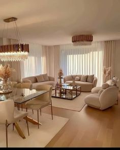 a living room filled with furniture and a chandelier above a glass top table