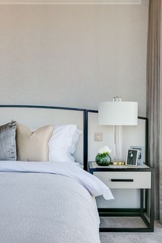 a white bed sitting next to a nightstand with a lamp on it's side