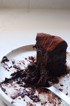 a piece of chocolate cake on a white plate with a knife and fork in it