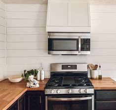 a stove top oven sitting inside of a kitchen next to wooden counter tops and cabinets