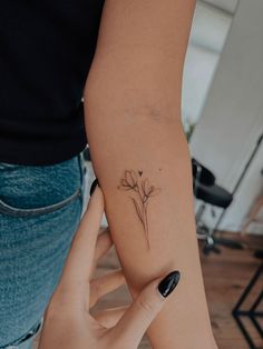 a woman's arm with a small flower tattoo on the left side of her arm