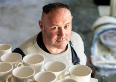 a man is looking at the camera with many cups in front of him