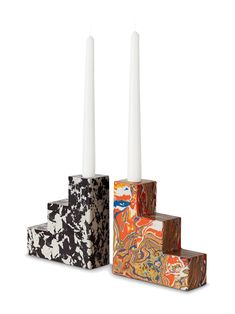 three candles sitting on top of each other in front of a white background and two different colored blocks