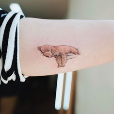 a woman's arm with a small tattoo of a dog on the back of her arm