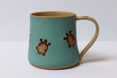 a blue and brown coffee mug with turtles on the inside is sitting on a white surface