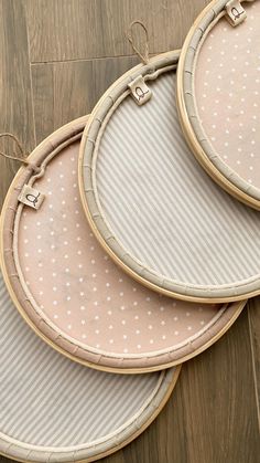 three round wooden frames with white polka dots on them sitting on a wood floor next to each other