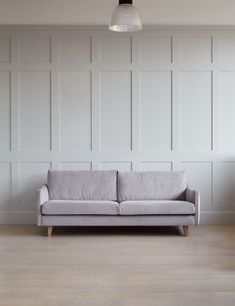 a gray couch sitting on top of a hard wood floor next to a white wall