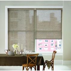 a dining room table with two chairs and a large window covered in roman blind shades