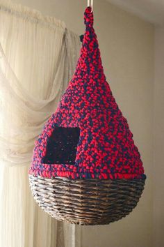 a red, white and blue bird feeder hanging from a ceiling