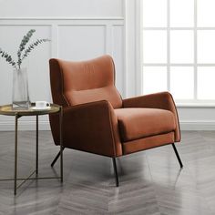 an orange chair sitting next to a table with a vase on it