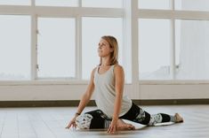 a woman is sitting on the floor doing yoga