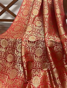 a red and gold brocaded fabric on a wooden chair